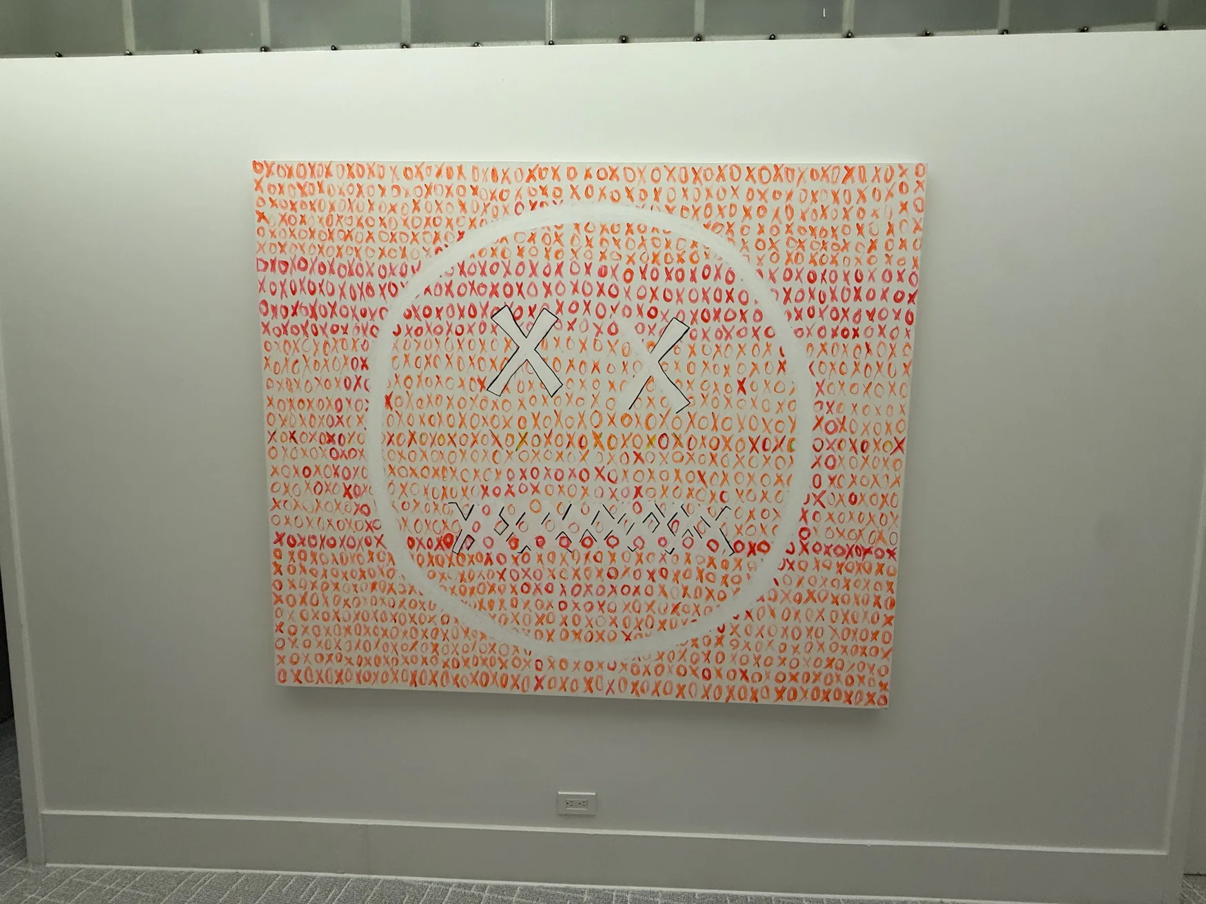 Large orange XO painting installed on a pale wall